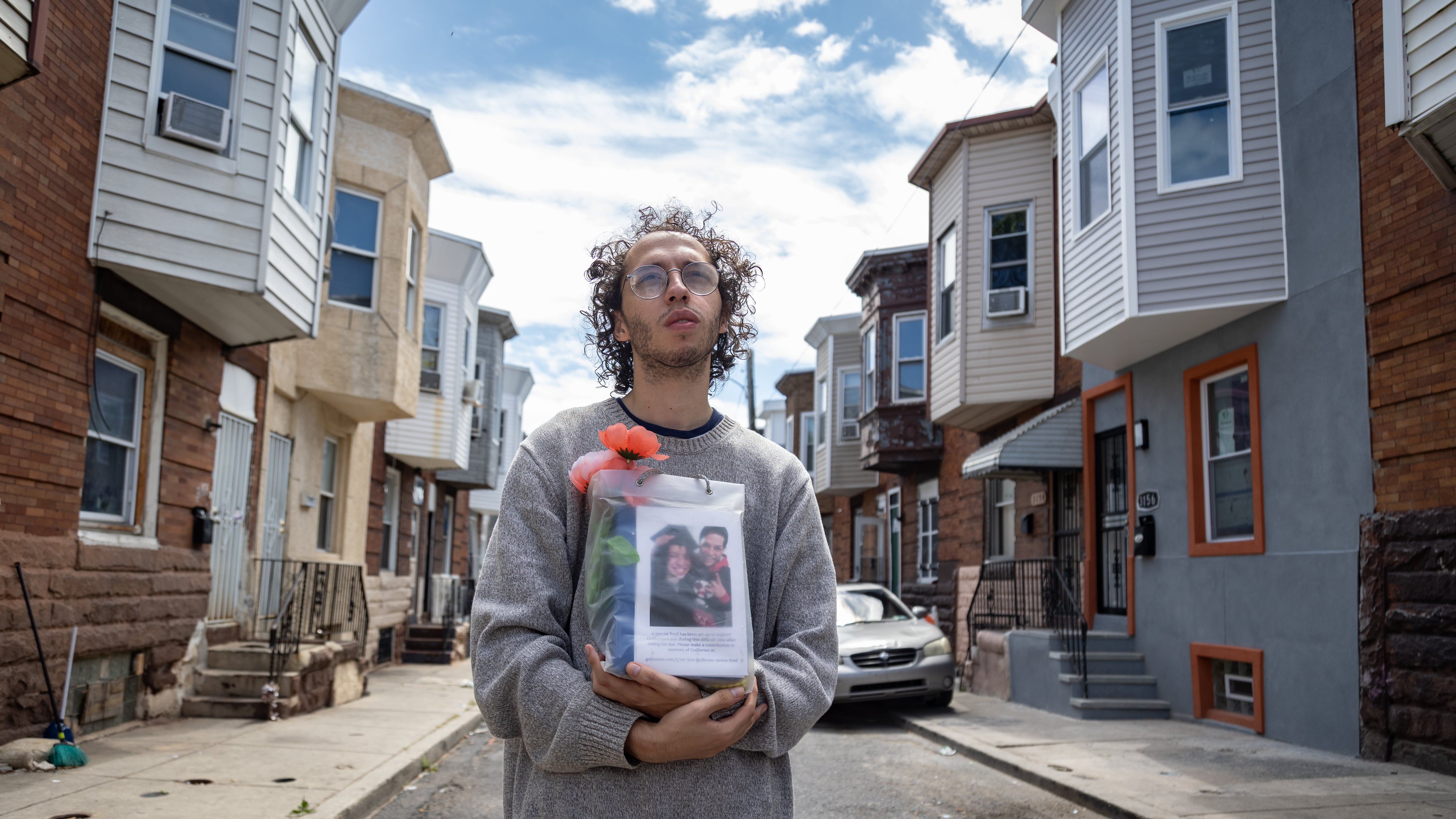 Guillermo Santos sostiene la urna con las cenizas de su padre, en la calle frente a la casa donde se crió en el barrio de Kensington en Filadelfia. Su papá, nacido en Puerto Rico, murió de una sobredosis.