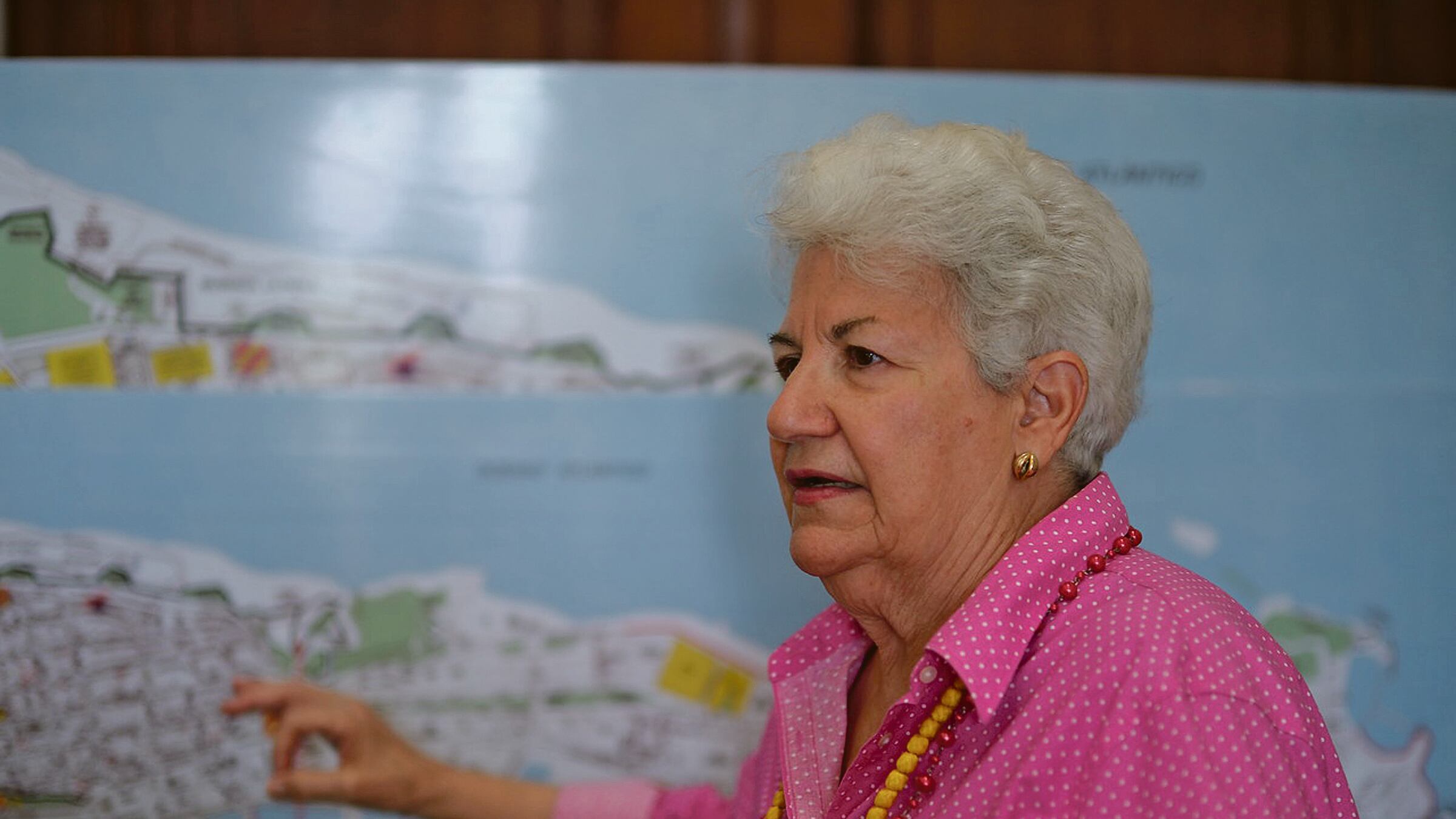 Margarita Gandía señala un mapa del Viejo San Juan mientras conversa mirando a la izquierda, hacia donde estaría la persona entrevistadora.