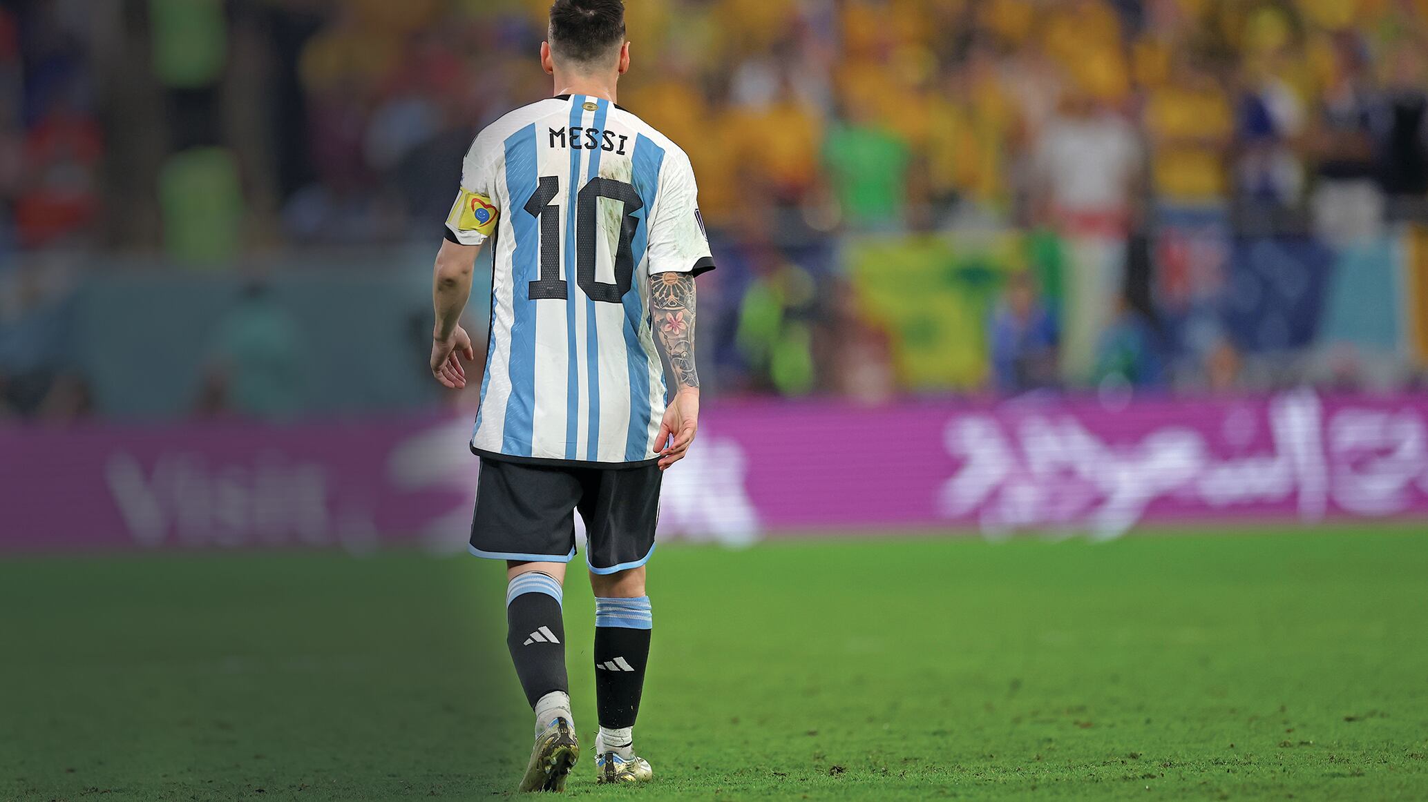 Lionel Messi camina en dirección a las gradas en un campo de golf. Se le ve de espaldas con la playera de la selección argentina y su número 10.