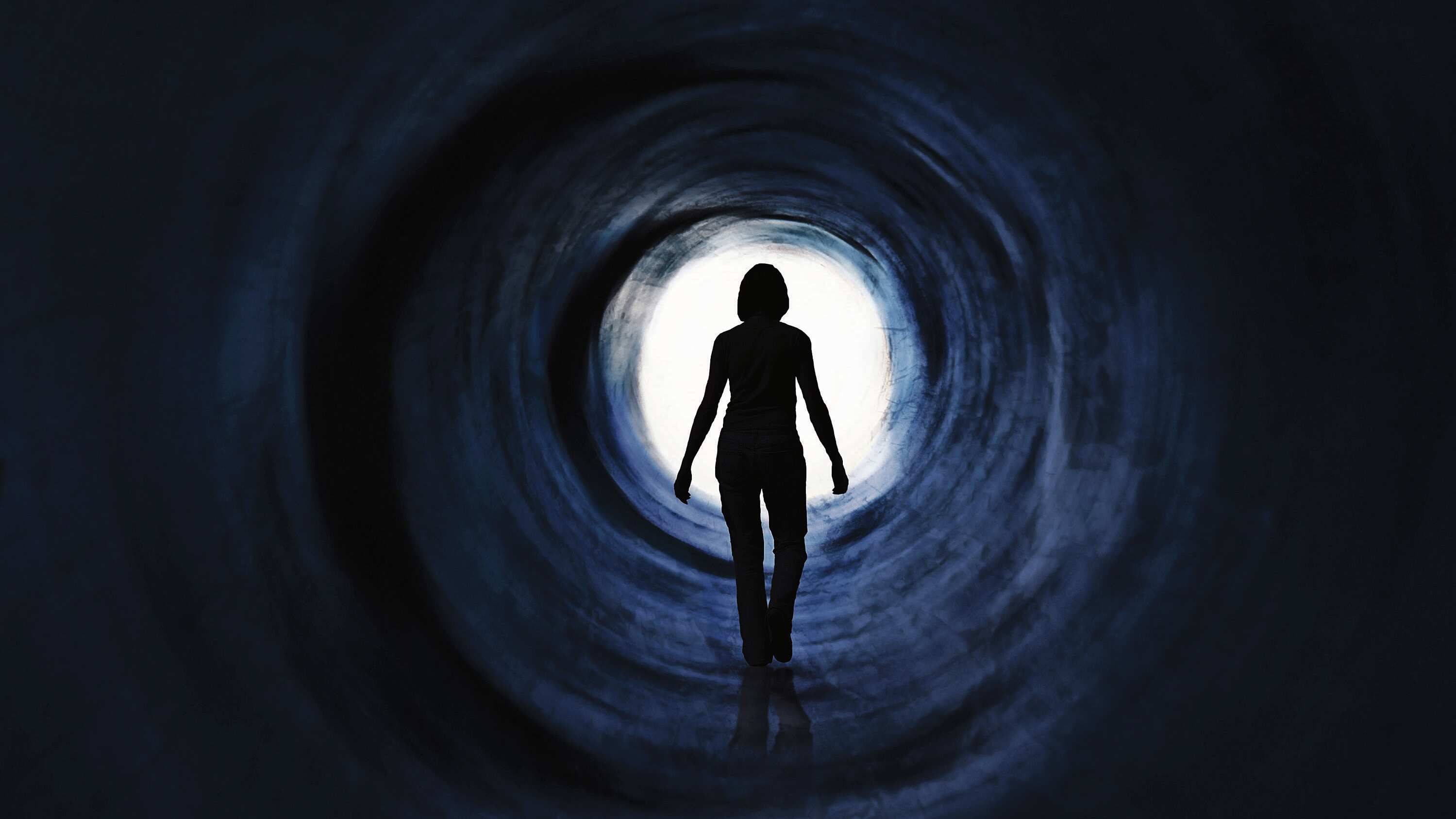 Una mujer camina hacia una luz deslumbrante. Puede simbolizar la huida, la búsqueda de salida o libertad e incluso la muerte o muerte clínica. Visión psicodélica. Manipulación de fotografías.