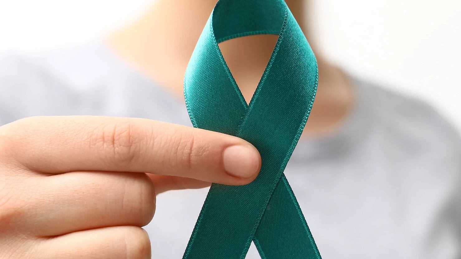 Una mujer sostiene un lazo color 'teal', o verde azulado, color que se utiliza como parte de la campaña de concientización sobre el cáncer cervical.