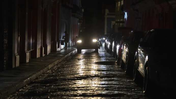 Los faros de un auto iluminan las calles empedradas del Viejo San Juan, Puerto Rico, durante un apagón en la isla, el 16 de abril de 2025. (AP Foto/Alejandro Granadillo)