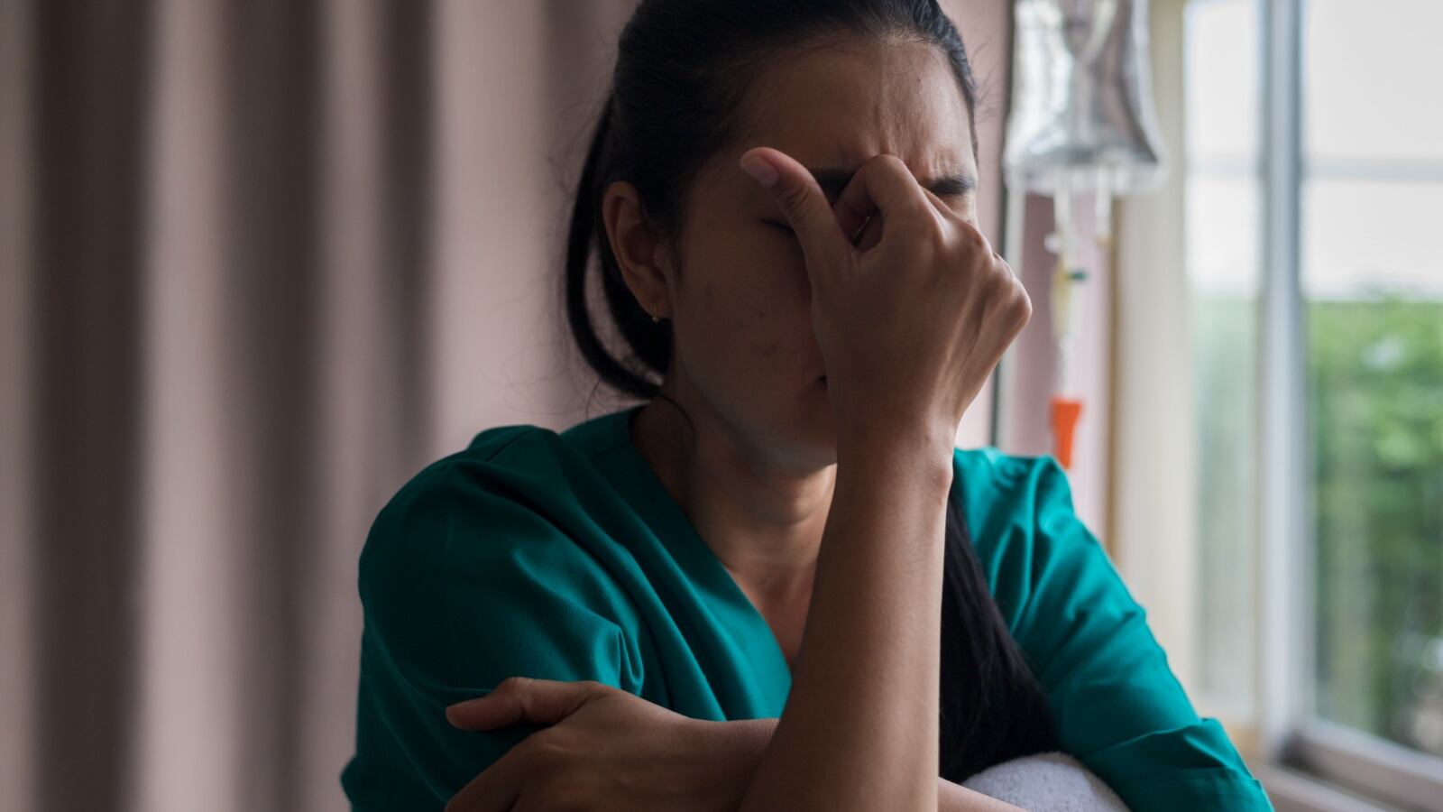 Una enfermera se coloca el la mano cerrada en su rostro reflejando frustración.