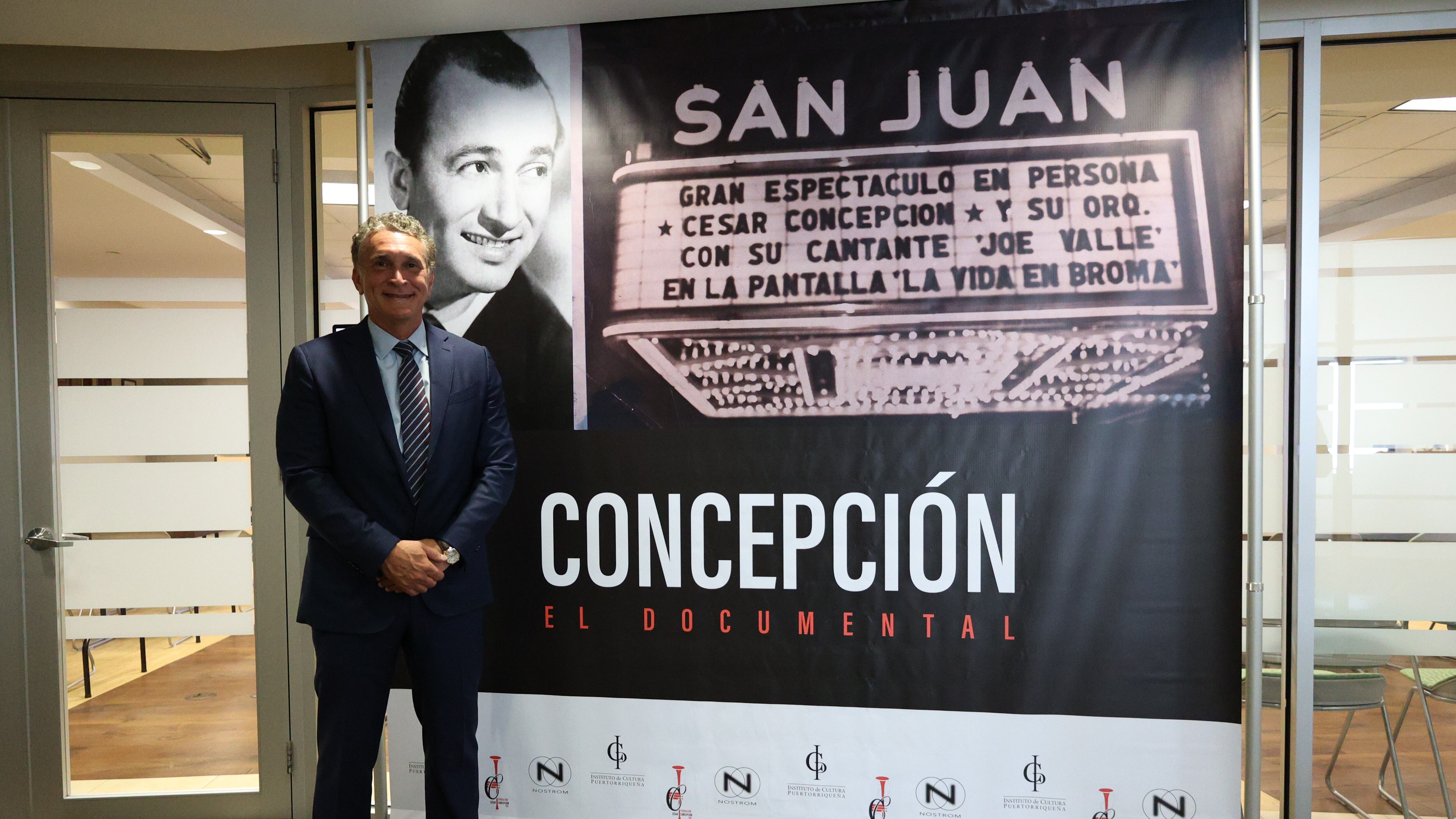 César Concepción De Peña (Hijo) junto al afiche del documental “César Concepción, El Trompetista”.