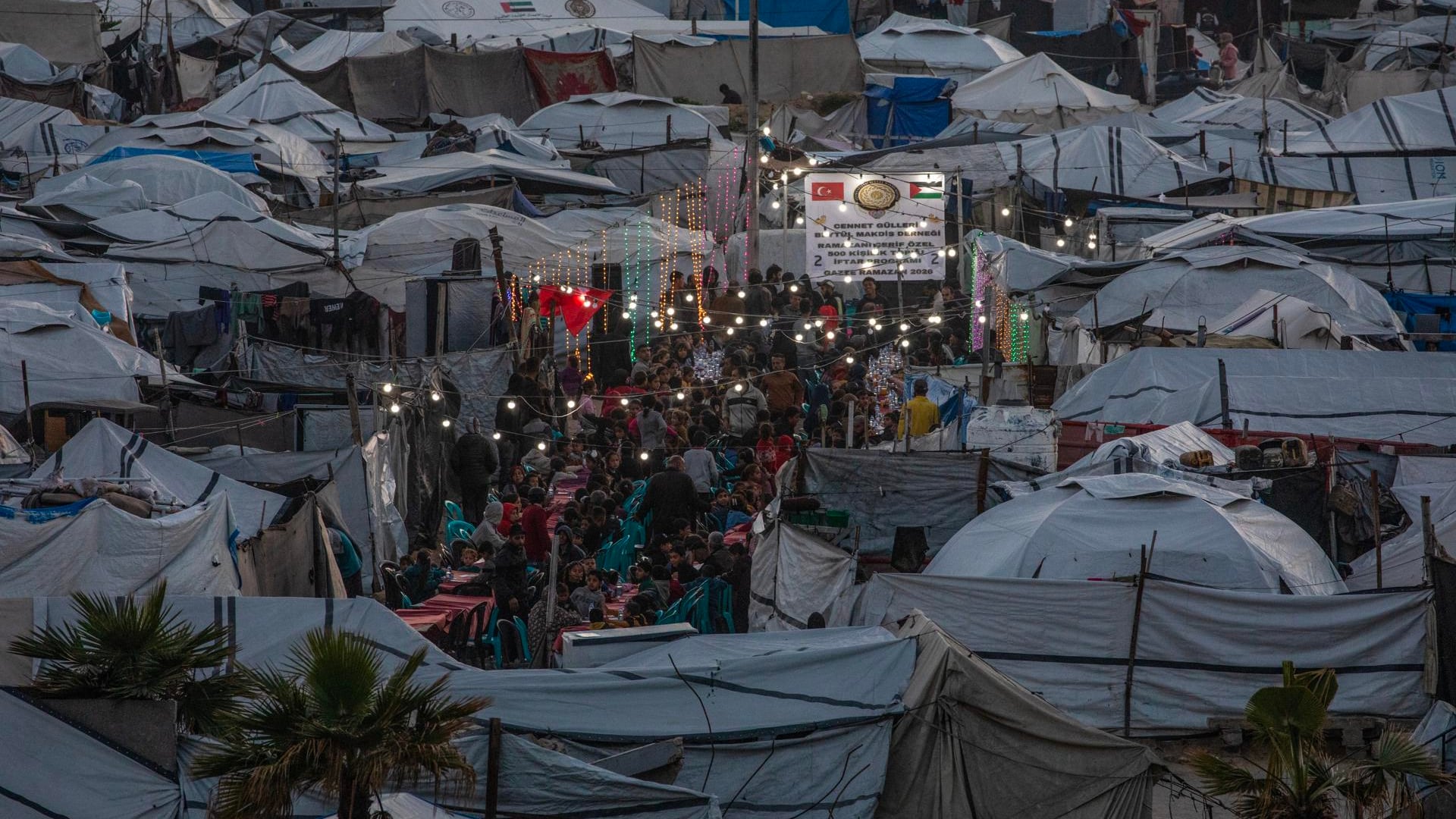 Palestinos desplazados se reúnen entre tiendas de campaña improvisadas para romper el ayuno con una comida iftar juntos durante el mes sagrado de ayuno de Ramadán en el oeste de Gaza, el 6 de marzo de 2026. EFE/MOHAMMED SABER