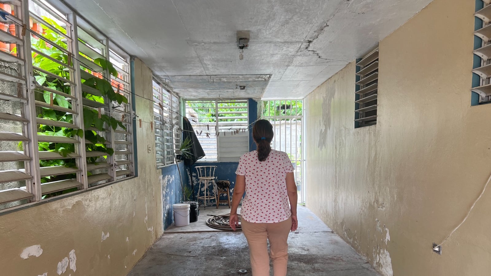 Mujer caminando en su hogar, la cual se encuentra en pobres condiciones.