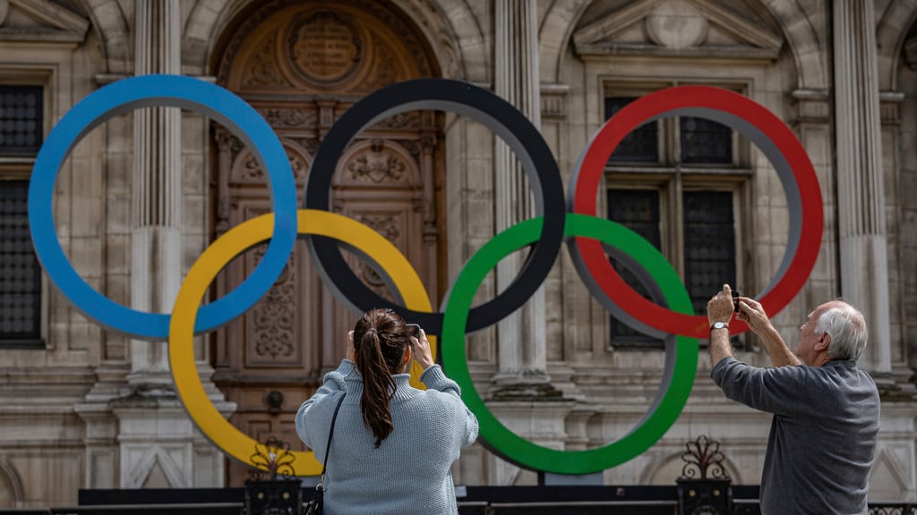 ARCHIVO - Dos personas toman fotos de los anillos olímpicos en el ayuntamiento de París, el 30 de abril de 2023. (AP Foto/Aurelien Morissard)
