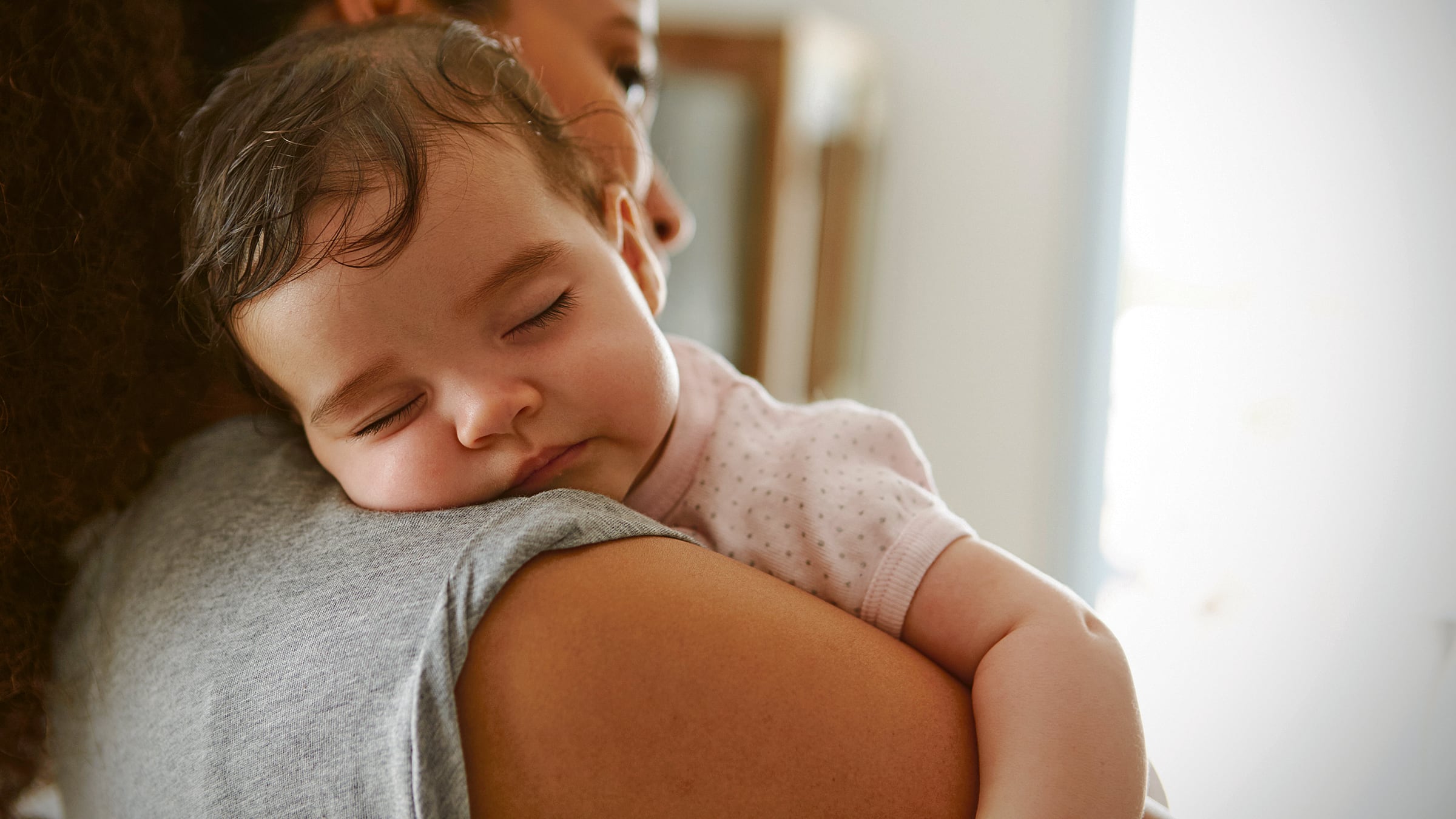 Una toma tipo close up de una madre con su bebé en brazos mientras se duerme.