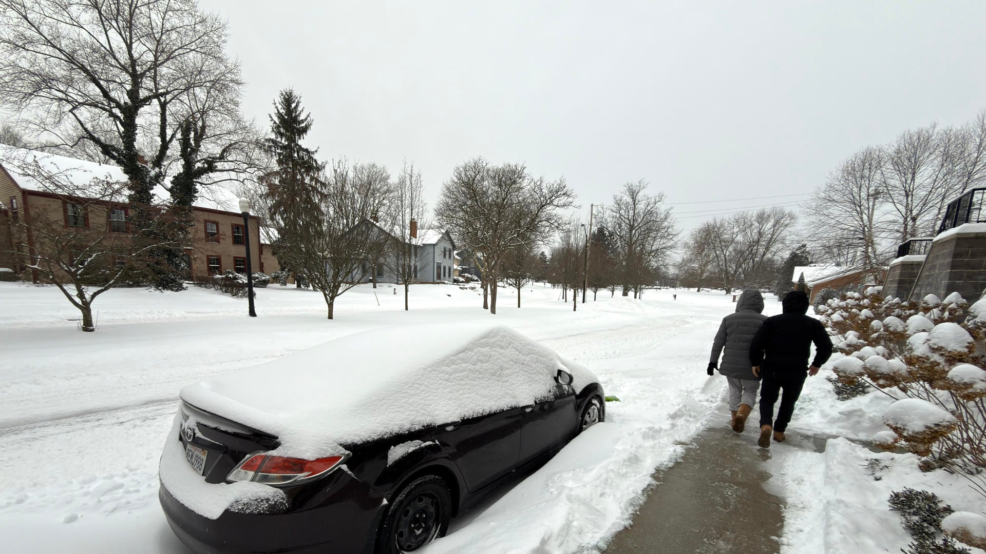 Dos personas caminan al lado de una calle afectada por la nieve este domingo en la ciudad de Hudson, Ohio (EE.UU.). EFE/ Rodrigo Sepúlveda