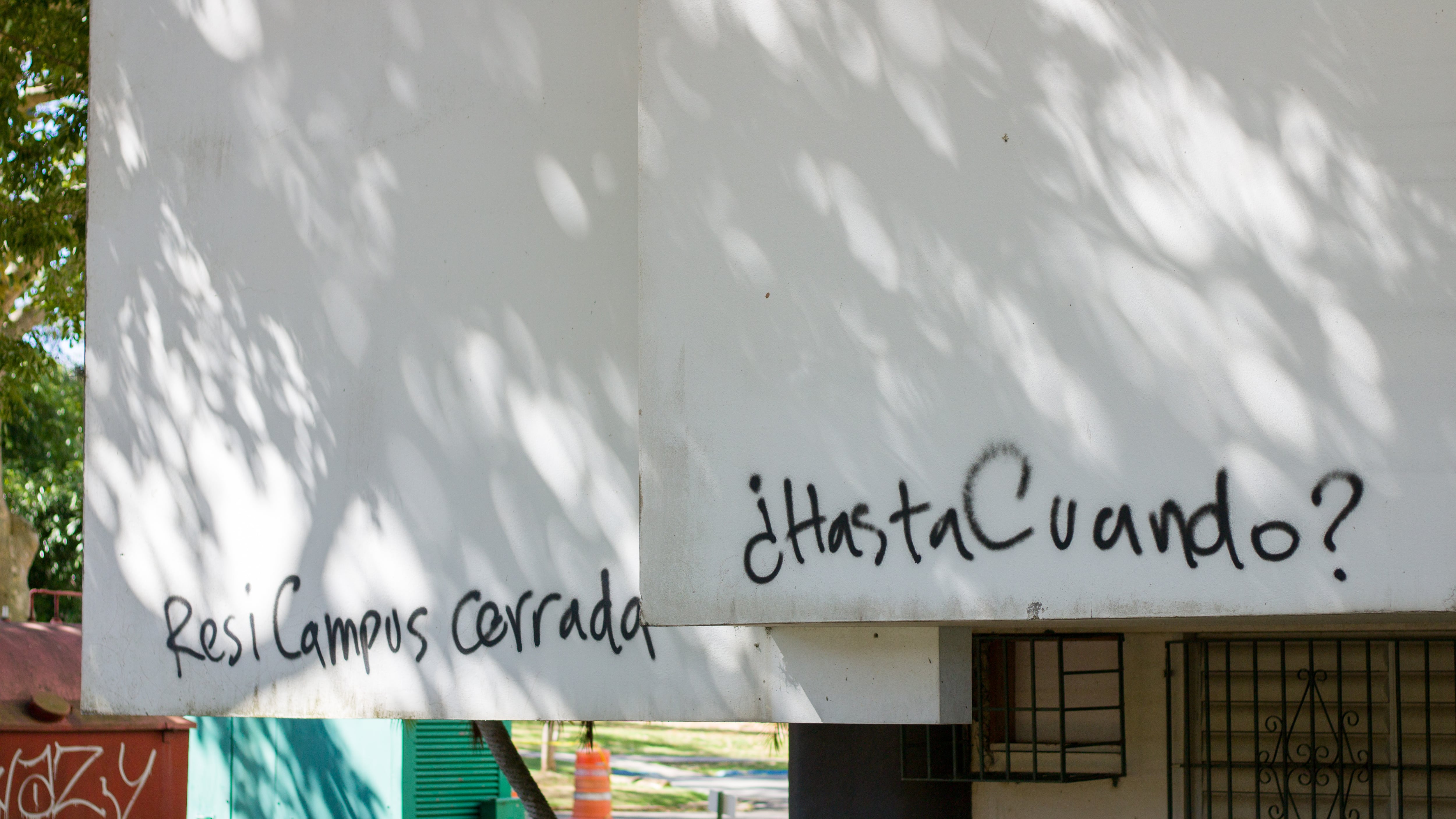 En una pared exterior de Resi Campus, un grafiti lee "Resi Campus cerrada. ¿Hasta cuándo?".