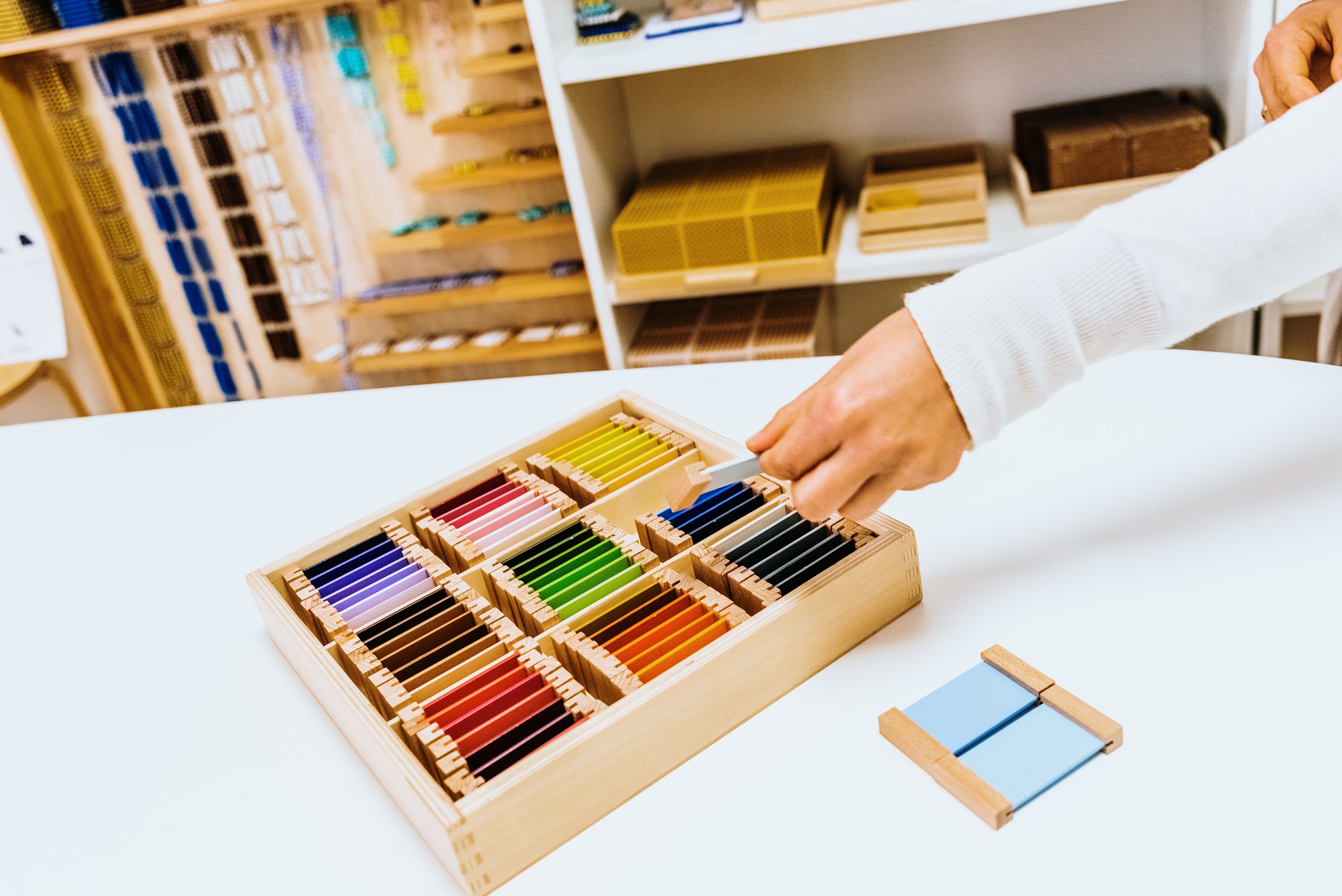 Hand of a student handling montessori material inside a classroom.