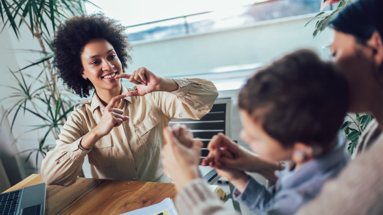 Una mujer enseña lenguaje de señas a un niño acompañado de su cuidadora.