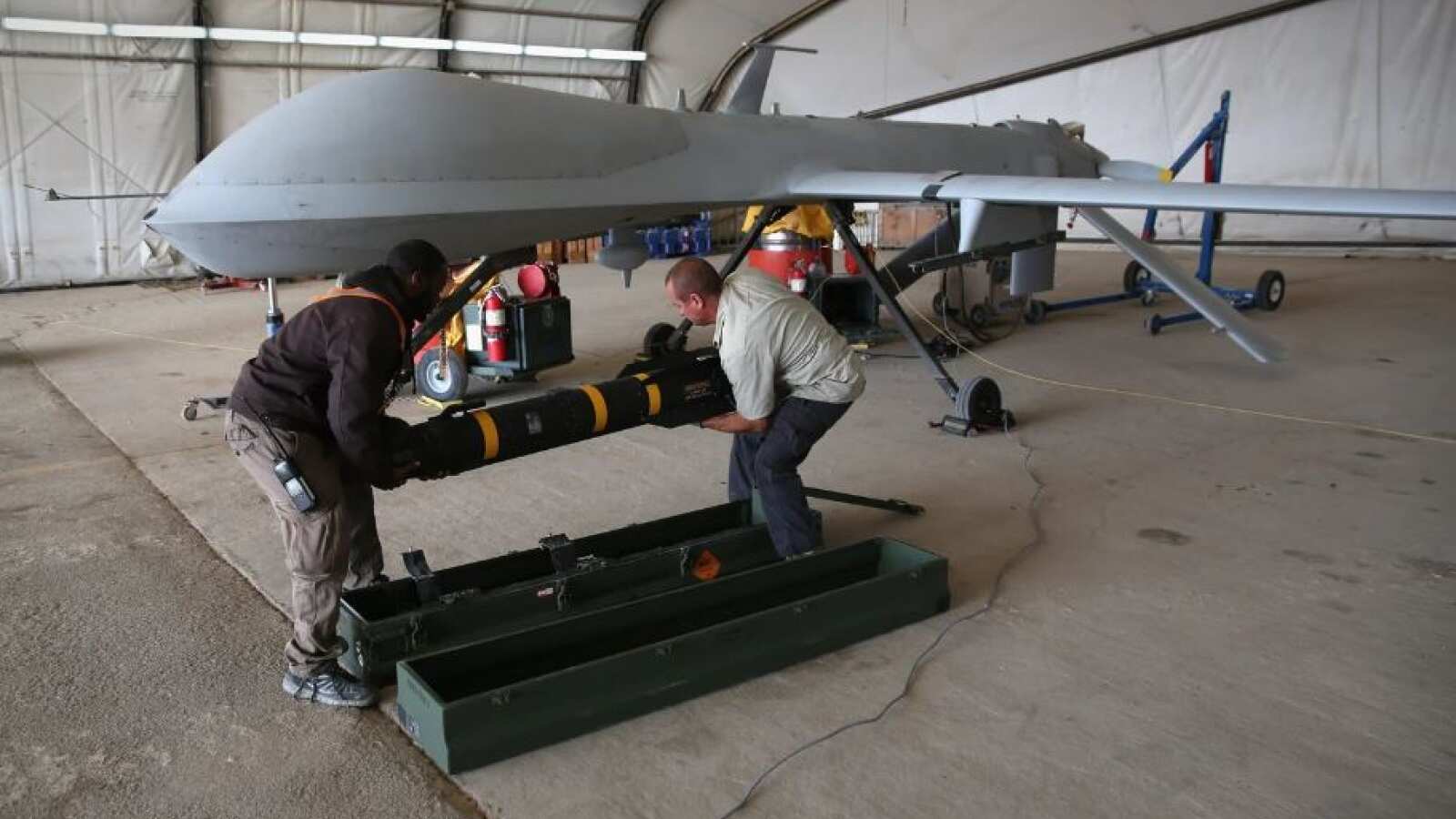 Trabajadores subcontratados cargan un misil Hellfire en un vehículo aéreo no tripulado (UAV) Predator MQ-1B de la Fuerza Aérea de EE UU.
