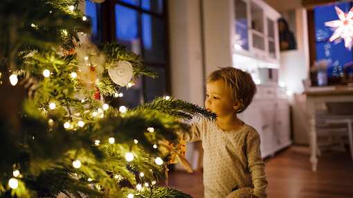 Un niño frente a un árbol de Navidad.