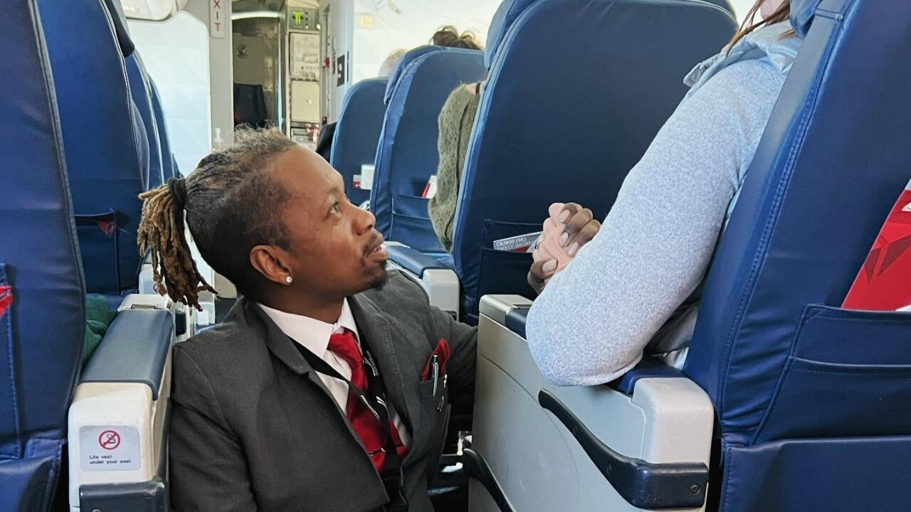 Momento en que el asistente de vuelo acompaña a la pasajera para calmar sus nervios.