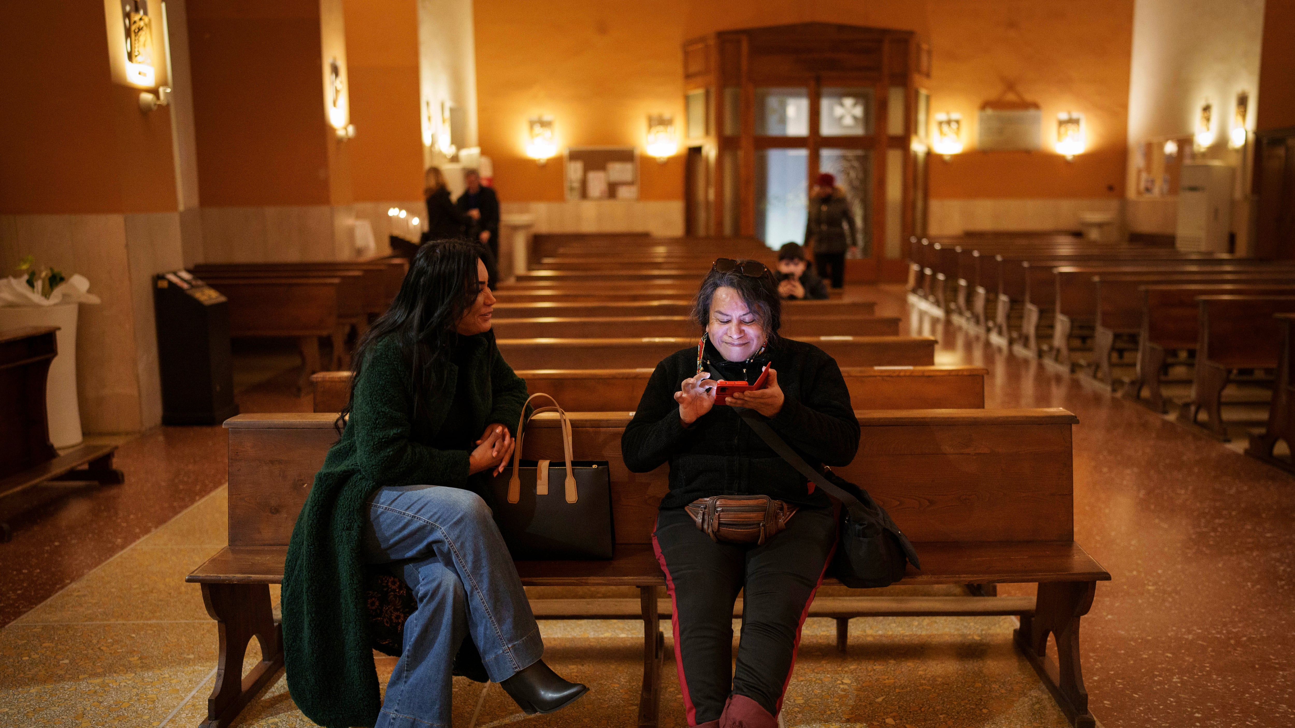 Carla Segovia, a la izquierda, y Minerva, que son trans, se sientan en la iglesia Bendita Virgen Inmaculada en Torvaianica, Italia, el jueves 27 de febrero de 2025. (AP Foto/Bernat Armangue)