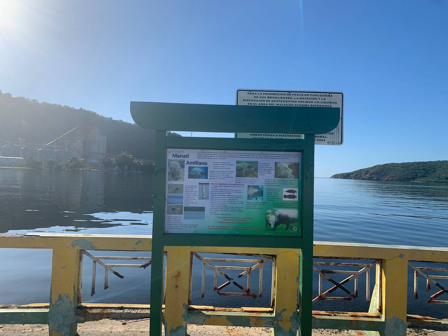 Letrero en la zona del malecón en la Bahía de Guánica escondido detrás de un boletín informativo sobre el manatí Antillano recientemente instalado.