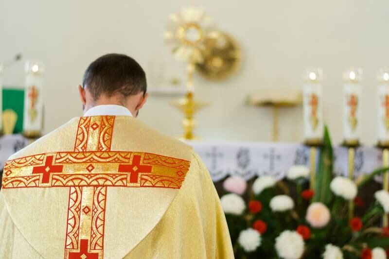 Sacerdote de Iglesia Católica orando frente altar.